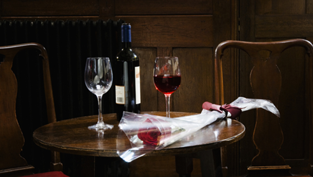 Rose, glasses and bottle of wine on table in wine bar