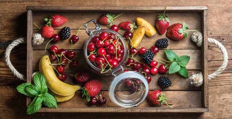 Healthy summer fruit variety. Sweet cherries, strawberries, blackberries, peaches, bananas and mint leaves in rustic wooden tray. Top view